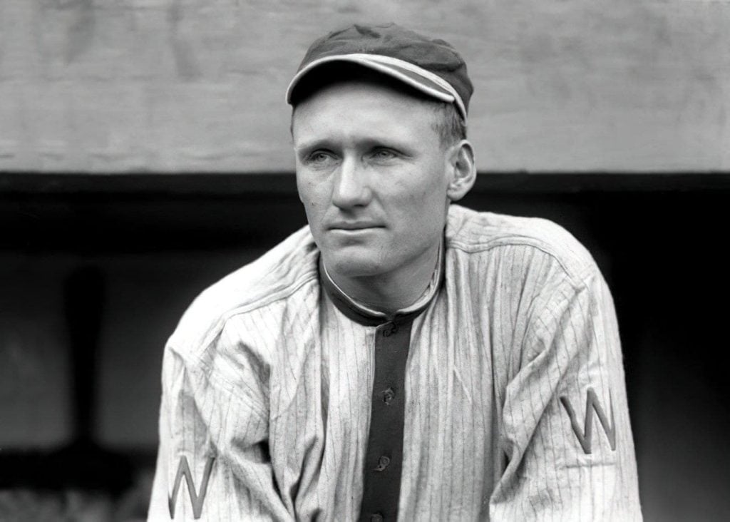 Walter Johnson stares into the distance while standing in the dugout