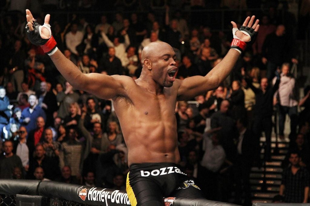 Anderson Silva sitting on the octagon wall and celebrating