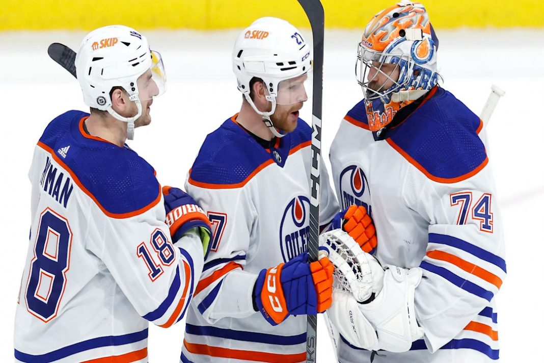 Three Edmonton Oilers skaters talking on the ice