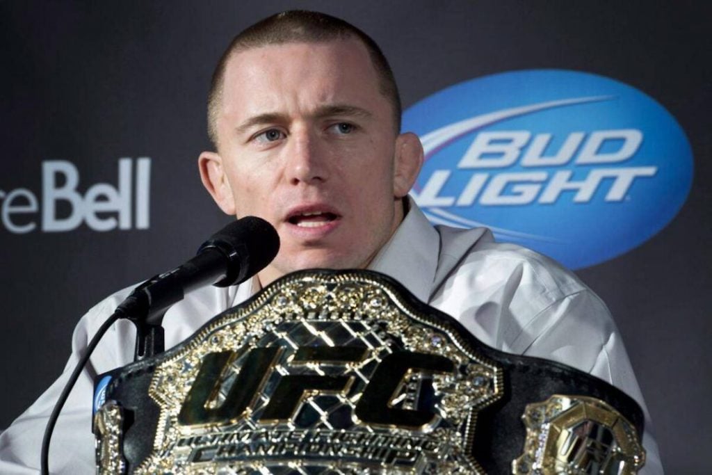 Georges St-Pierre sitting with his UFC belt at a press conference