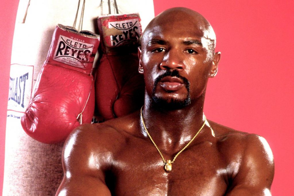 Marvin Hagler posing for a photo with boxing gloves behind him