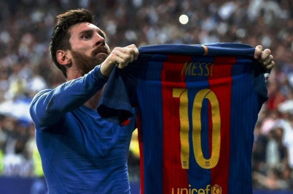 Lionel Messi holds his shirt up in front of Barcelona fans.